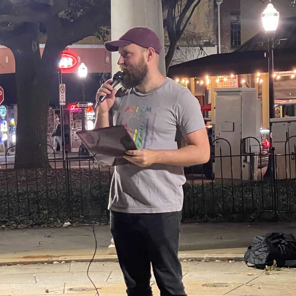 man speaking at an outdoor event at night