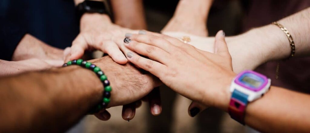 Team members stacking hands as a sign of unity and teamwork.