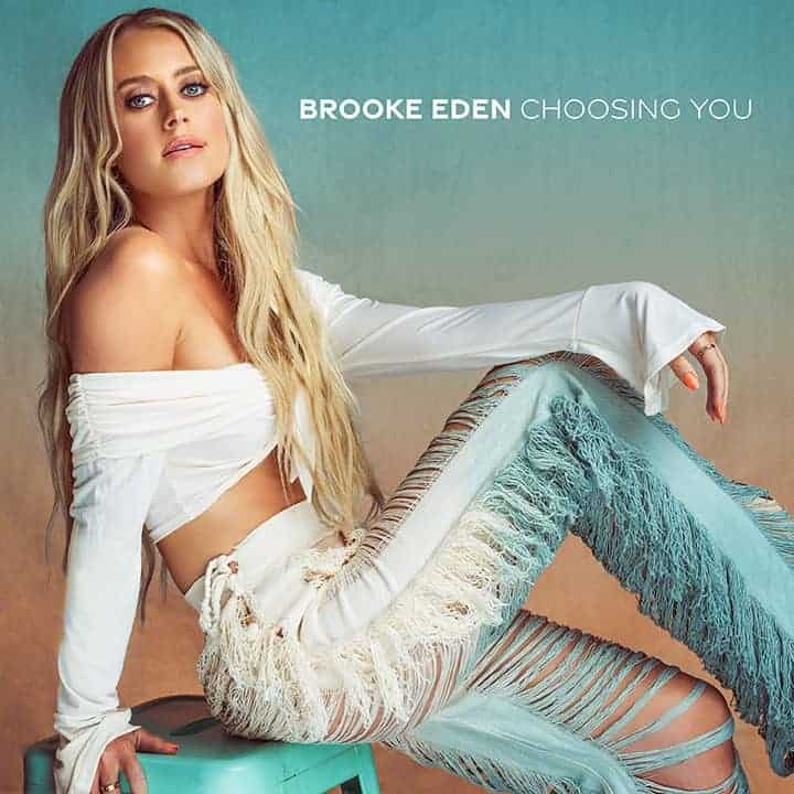 Woman posing on a stool in stylish attire with text "brooke eden choosing you" indicating a music album or single cover.