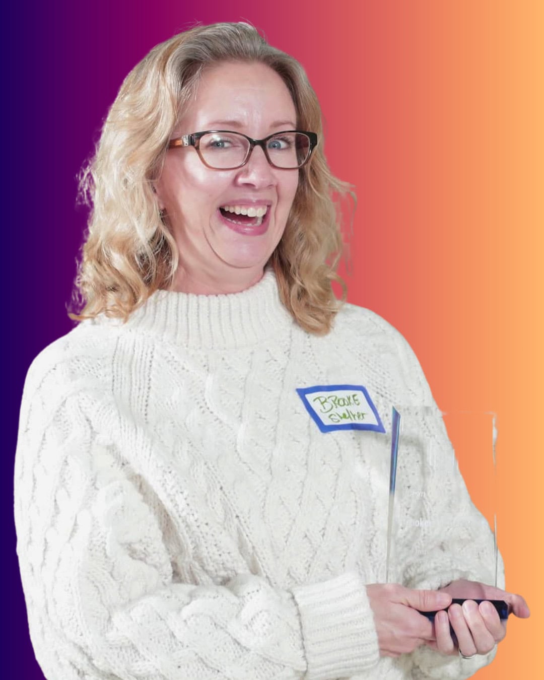 BrookeThistlethwaite A woman with blonde hair and glasses, wearing a white sweater and a name tag, holds a clear award against a colorful gradient background.