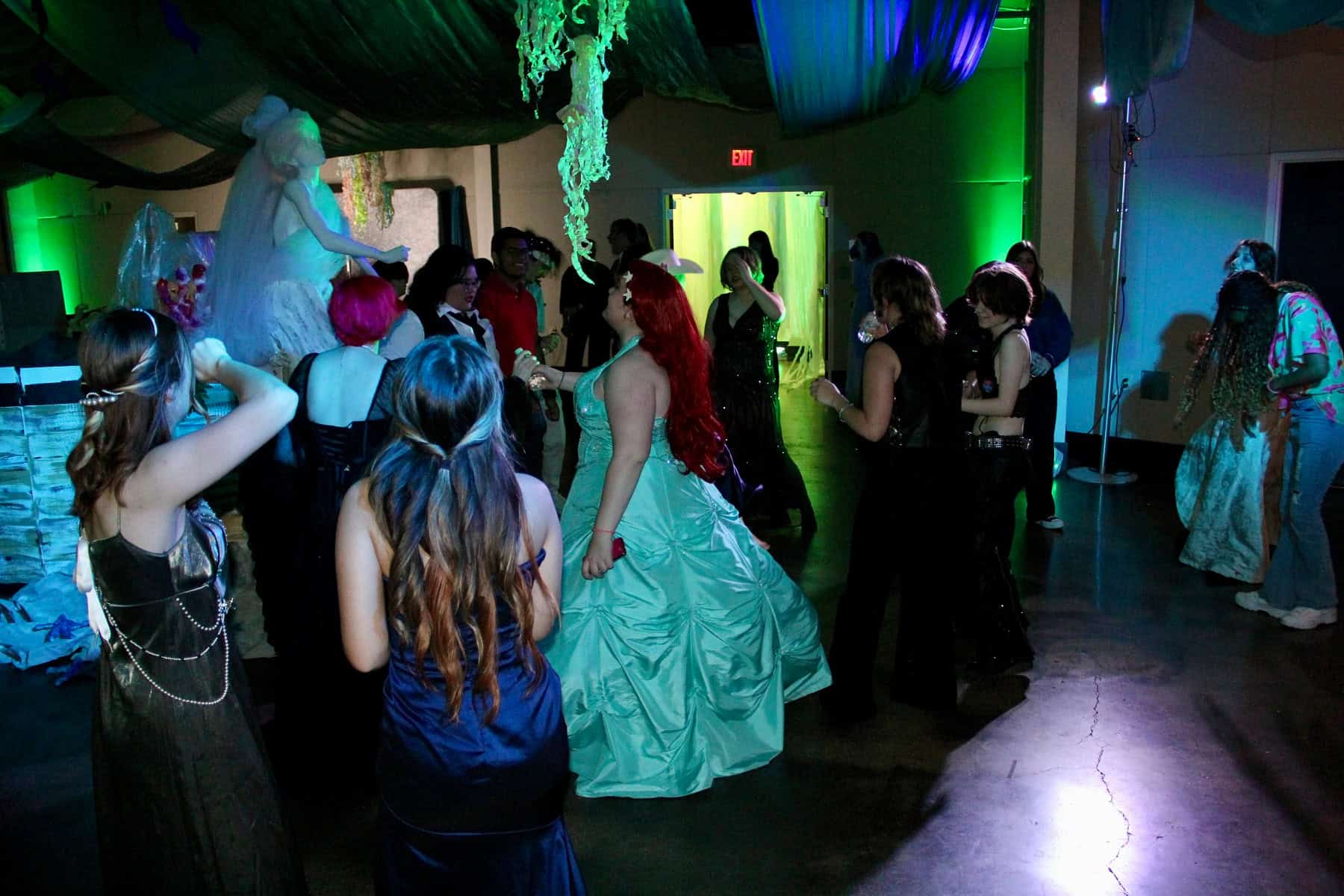 People dancing and socializing at a costume party with colorful lighting and festive decorations.