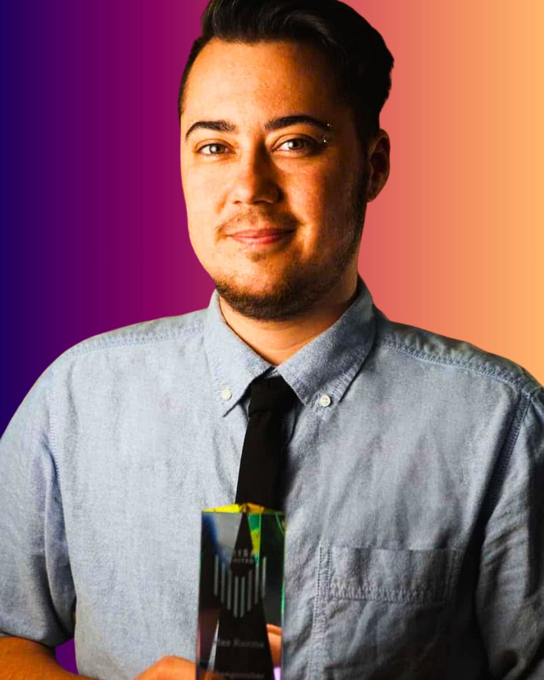 MaxwellKuzma Person with short dark hair, wearing a blue button-up shirt and black tie, holds a glass award against a gradient background from purple to orange.