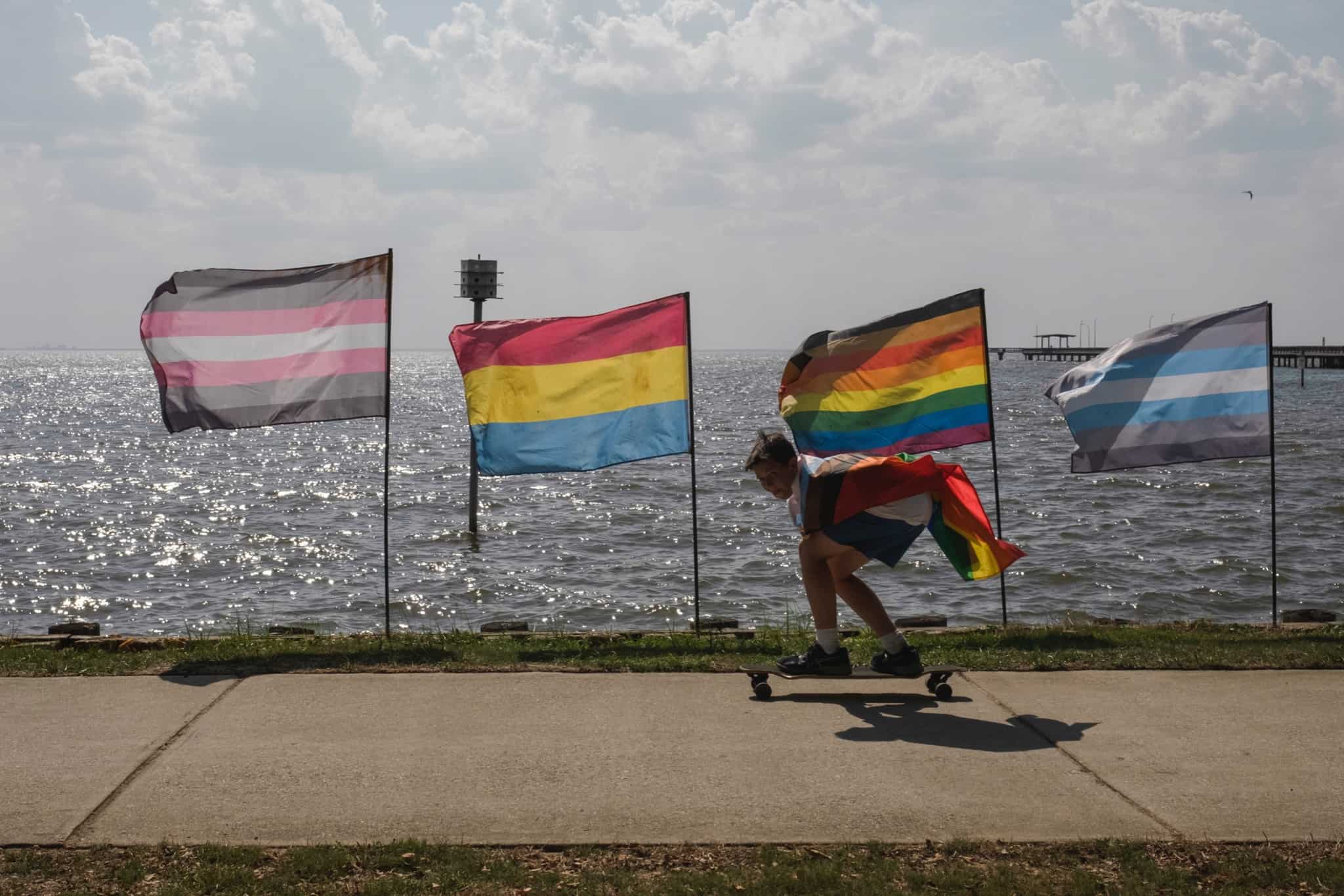 row of pride flags in the wind on the bay