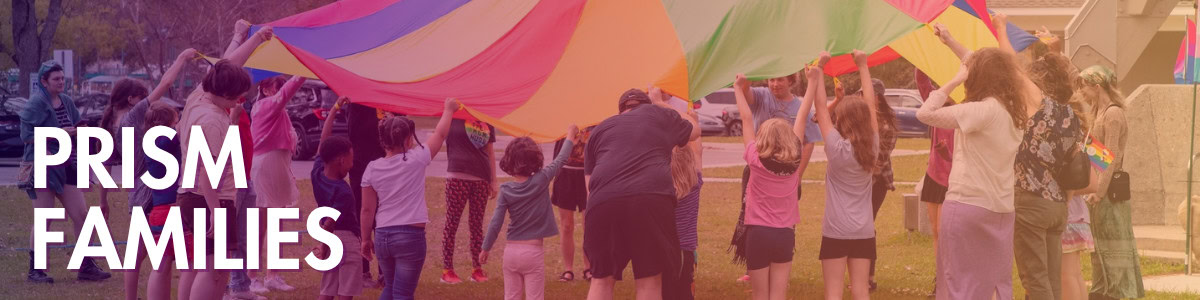 A group of adults and children hold up a large, colorful parachute outdoors on a grassy area, with the words “PRISM FAMILIES” on the left.