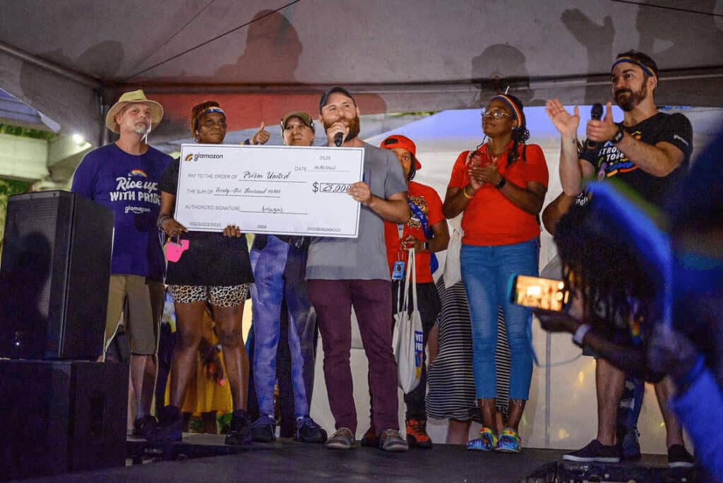 Group of individuals on a stage presenting a large ceremonial check to a recipient during an event.