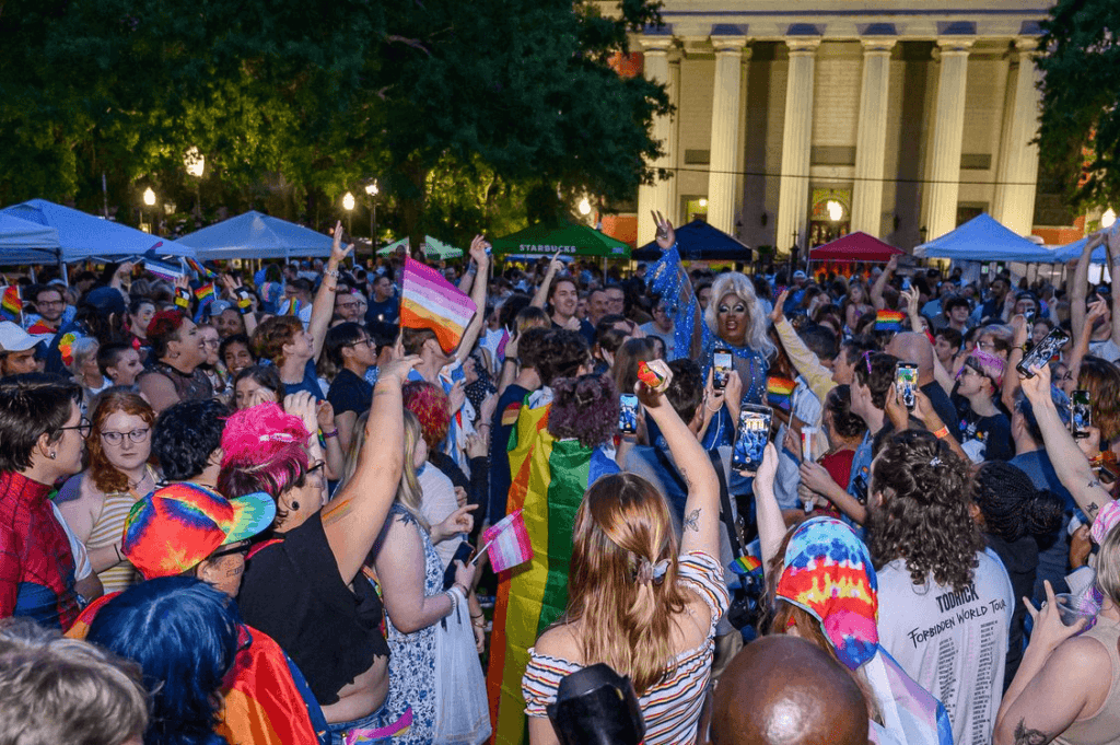A vibrant pride celebration with an enthusiastic crowd and a performer engaging the audience.
