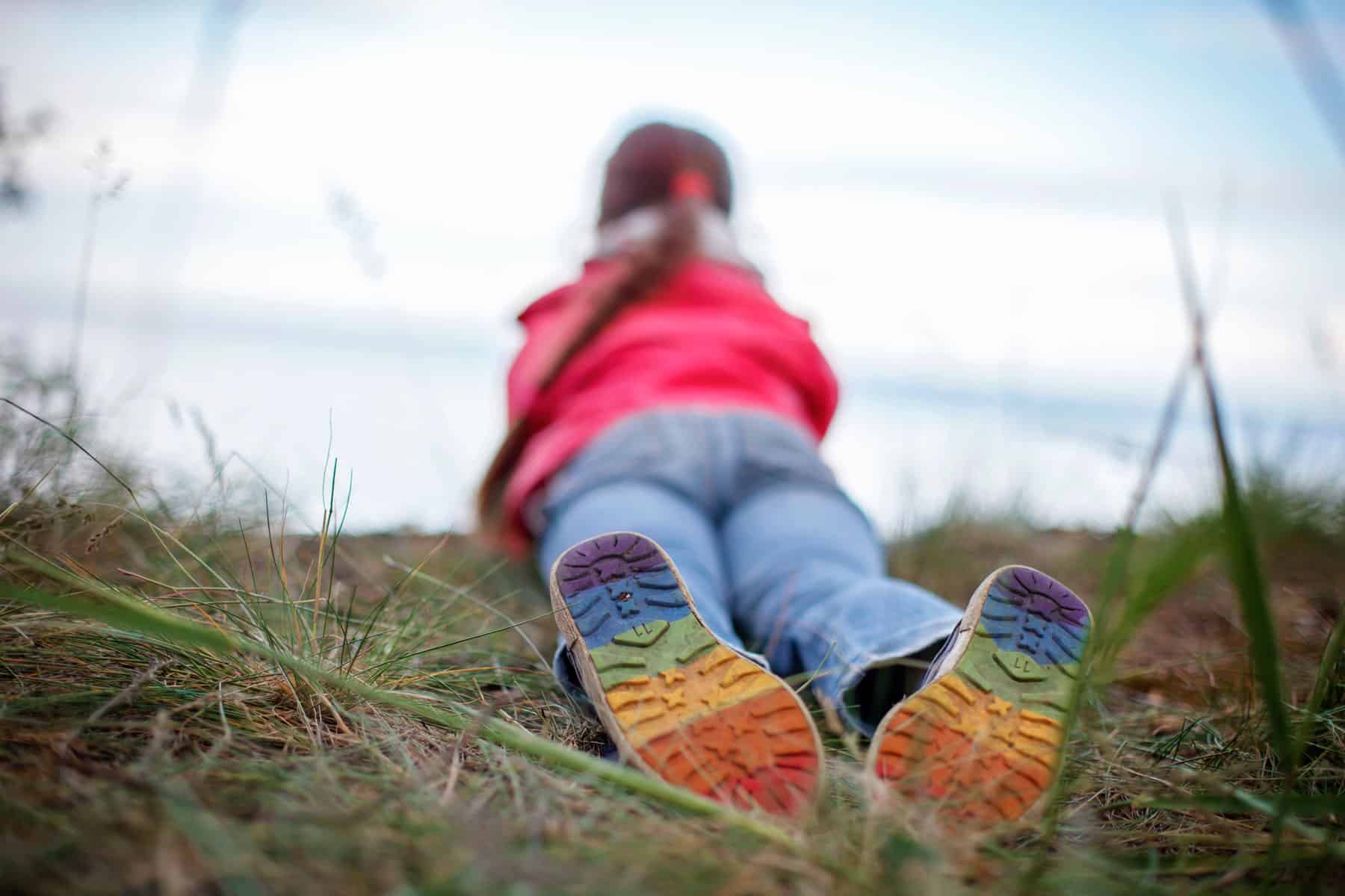 Girl laying on the ground with rainbow colored shoes